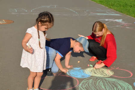 Child drawing sun and house on asphalt in a park on the playground or sidewalk, happy childhood, summer vacation, entertainment for childrenの写真素材