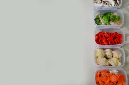 Trays with raw vegetables for freezing. Stocking up for winter storage in plastic containers, puts in a box to freeze red bell peppers, broccoli, cauliflower, carrotsの写真素材