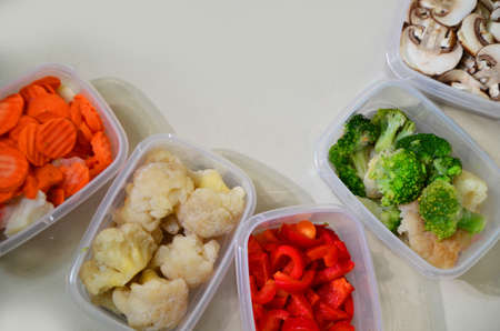 Trays with raw vegetables for freezing. Stocking up for winter storage in plastic containers, puts...
