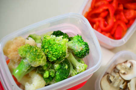 Trays with raw vegetables for freezing. Stocking up for winter storage in plastic containers, puts in a box to freeze red bell peppers, broccoli, cauliflower, carrotsの写真素材