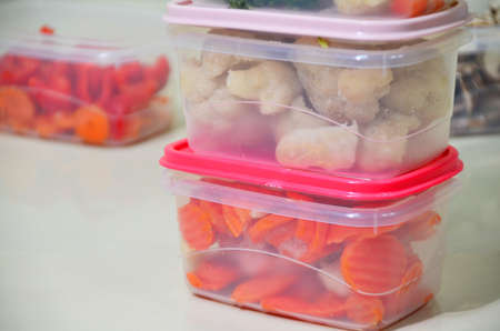 Trays with raw vegetables for freezing. Stocking up for winter storage in plastic containers, puts in a box to freeze red bell peppers, broccoli, cauliflower, carrotsの写真素材