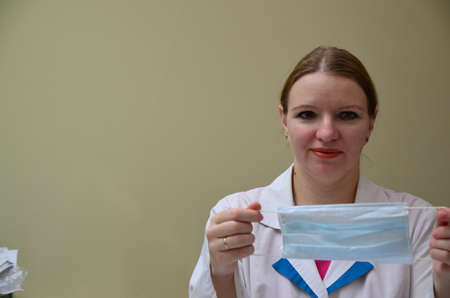 Portrait of female doctor in special surgical sterile protective clothing. puts on a mask and gloves before receiving a patient in the officeの写真素材