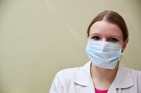 Portrait of female doctor in special surgical sterile protective clothing. puts on a mask and gloves before receiving a patient in the officeの写真素材