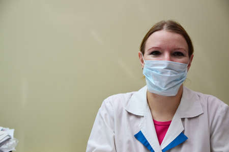 Portrait of female doctor in special surgical sterile protective clothing. puts on a mask and gloves before receiving a patient in the officeの写真素材
