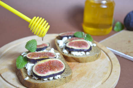 Sandwiches with ricotta, fresh figs, walnuts and honey. Canape or crostini with toasted baguette, cheese, jam, Delicious appetizer, ideal as an aperitif. Selective focusの写真素材