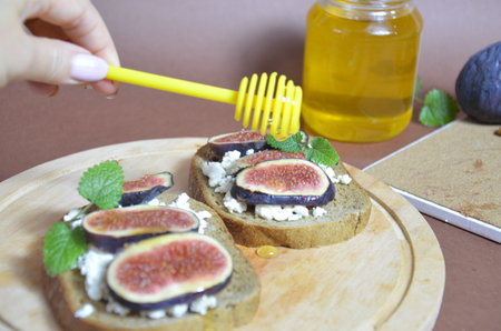 Sandwiches with ricotta, fresh figs, walnuts and honey. Canape or crostini with toasted baguette, cheese, jam, Delicious appetizer, ideal as an aperitif. Selective focusの写真素材