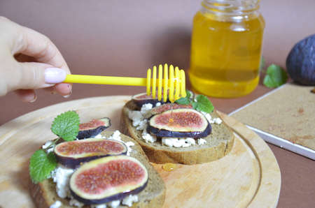 Sandwiches with ricotta, fresh figs, walnuts and honey. Canape or crostini with toasted baguette, cheese, jam, Delicious appetizer, ideal as an aperitif. Selective focusの写真素材