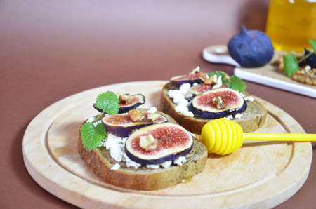 Sandwiches with ricotta, fresh figs, walnuts and honey. Canape or crostini with toasted baguette, cheese, jam, Delicious appetizer, ideal as an aperitif. Selective focusの写真素材