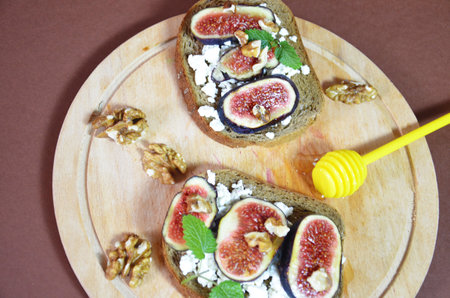 Sandwiches with ricotta, fresh figs, walnuts and honey. Canape or crostini with toasted baguette, cheese, jam, Delicious appetizer, ideal as an aperitif. Selective focusの写真素材
