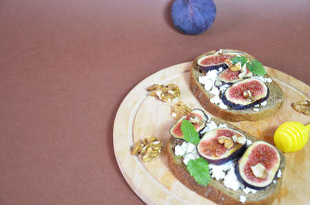 Sandwiches with ricotta, fresh figs, walnuts and honey. Canape or crostini with toasted baguette, cheese, jam, Delicious appetizer, ideal as an aperitif. Selective focusの写真素材
