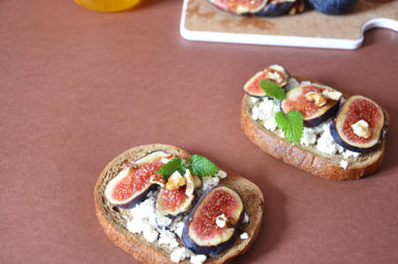 Sandwiches with ricotta, fresh figs, walnuts and honey. Canape or crostini with toasted baguette, cheese, jam, Delicious appetizer, ideal as an aperitif. Selective focusの写真素材