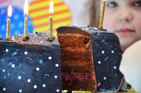 cut a big chocolate cake. happy little girl celebrates birthday, balloons and decorations. the candles on the cake blow out. Happy group of children having fun at birthday partyの写真素材