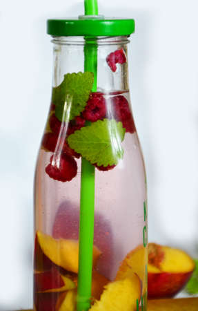 Healthy detox fruit infused flavored water. Summer refreshing homemade cocktail with fruits and thyme on white in a bottle on a white background.の写真素材