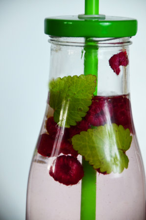 Healthy detox fruit infused flavored water. Summer refreshing homemade cocktail with fruits and thyme on white in a bottle on a white background.の写真素材