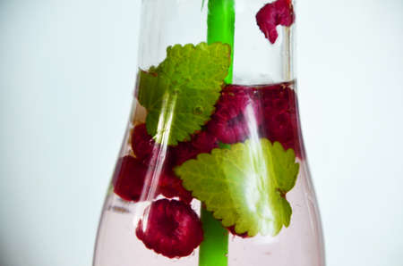 Healthy detox fruit infused flavored water. Summer refreshing homemade cocktail with fruits and thyme on white in a bottle on a white background.の写真素材