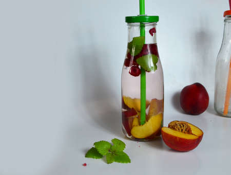 Healthy detox fruit infused flavored water. Summer refreshing homemade cocktail with fruits and thyme on white in a bottle on a white background.の写真素材