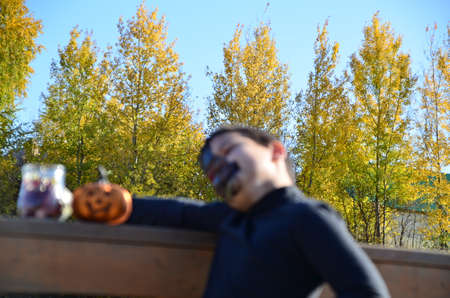 boy with black makeup for halloween, zombie. Scary little boy smiling wearing skull makeup for halloween halloween pumpkin lantern, sweetsの写真素材
