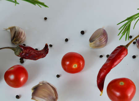Garlic falling in air with pepper and herbs like rosemary and basil leaves on white background. Spicy food concept. abstract background, no focusの写真素材