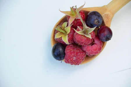 forest summer berries raspberries and blueberries in a spoon on a white table