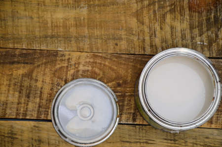 open, painted bucket and paintbrush on a wooden background. Painting tools and accessories for home renovationの写真素材