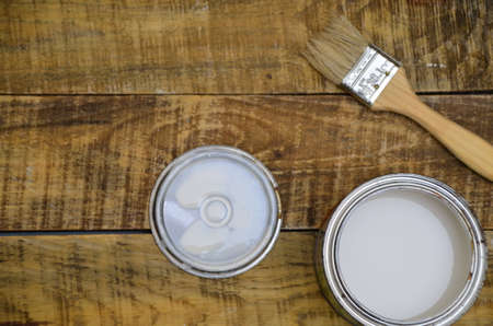 open, painted bucket and paintbrush on a wooden background. Painting tools and accessories for home renovationの写真素材