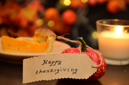 pumpkin with a Happy Thanksgiving paper price tag - holiday shopping concept Happy Thanksgiving gift tag pumpkin pie on a festive table, next to a candleの写真素材