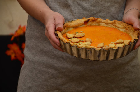 girl holding in her arms. Fresh Homemade Pumpkin Pie made for Thanksgiving. celebrating a holiday in autumn or winter. homemade bakingの写真素材