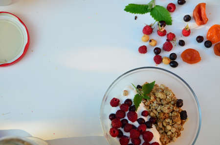 Healthy breakfast bowl with homemade granola. proper nutrition bowl of oat granola with yogurt, fresh raspberries, blueberries, strawberries, blackberries nuts with spoon on white for healthy food.の写真素材