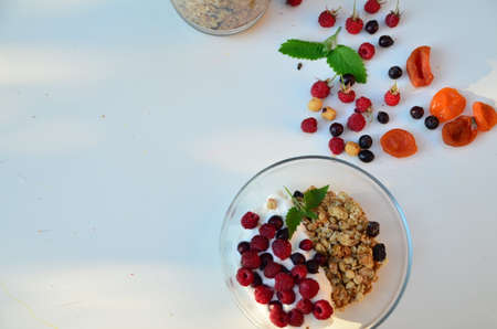 Healthy breakfast bowl with homemade granola. proper nutrition bowl of oat granola with yogurt, fresh raspberries, blueberries, strawberries, blackberries nuts with spoon on white for healthy food.の写真素材