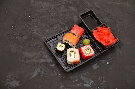 Eating Sushi with chopsticks. Sushi roll japanese food in restaurant. California Sushi roll set with salmon, vegetables, flying fish roe and caviar closeup. Japanese restaurant menuの写真素材