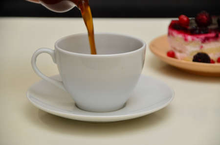 Fruit dessert and coffee low-calorie dessert with berries and cream. pour coffee and cream into a cup.の写真素材