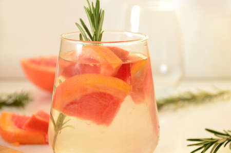 Refreshing grapefruit cocktail with ice and rosemary on a white background. rosemary on the table. or detox water or smoothie. low calorie diet.の写真素材