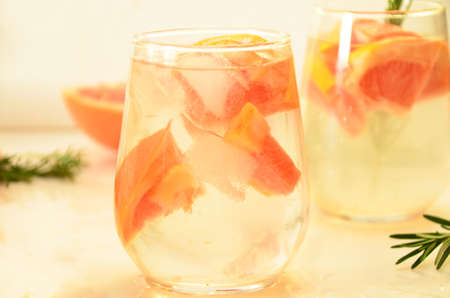 Refreshing grapefruit cocktail with ice and rosemary on a white background. rosemary on the table. or detox water or smoothie. low calorie diet.の写真素材