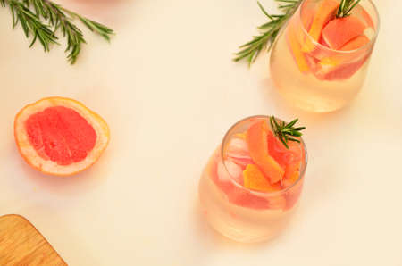 Refreshing grapefruit cocktail with ice and rosemary on a white background. rosemary on the table. or detox water or smoothie. low calorie diet.の写真素材