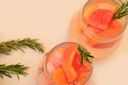 Refreshing grapefruit cocktail with ice and rosemary on a white background. rosemary on the table. or detox water or smoothie. low calorie diet.の写真素材