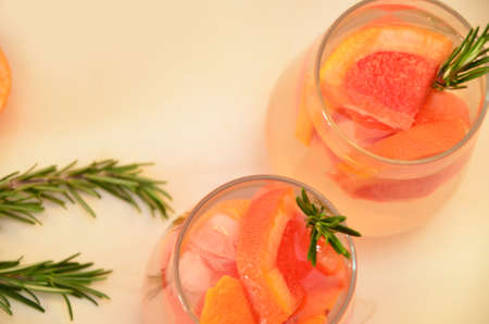 Refreshing grapefruit cocktail with ice and rosemary on a white background. rosemary on the table. or detox water or smoothie. low calorie diet.の写真素材