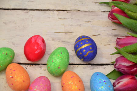 Colorful easter quail eggs and tulips on white wooden background with . flat lay. spring...