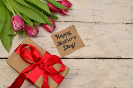 mother's day, woman's day. tulips ,presents on wooden white background, greeting card with the inscription happy mother's day, heartsの写真素材