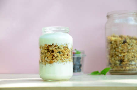 Healthy breakfast bowl with homemade granola. proper nutrition bowl of oat granola with yogurt, fresh raspberries, blueberries, strawberries, blackberries nuts with spoon on white for healthy foodの写真素材