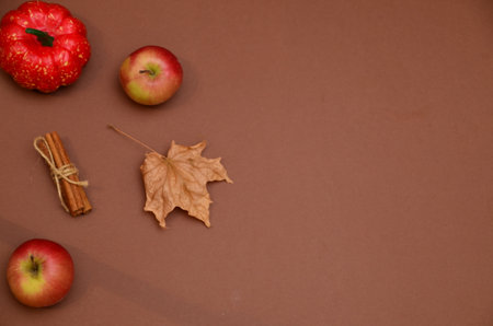 Autumnal composition with copy space. Fall leaves, apple, cinnamon, pumpkin on dark brown. Thanksgiving day concept. Flat lay, top viewの写真素材