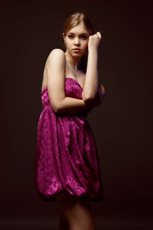 Seductive young woman wearing pink dress on a dark backgroundの写真素材
