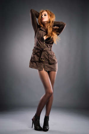 Attractive red-haired girl wearing casual dress and high heels shoes . Studio shotの写真素材