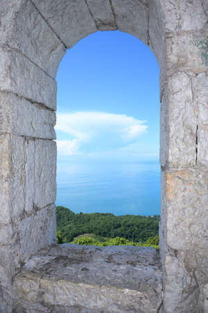 Kind on sea coast through a window of a stone towerの写真素材