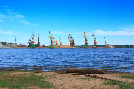 view  of cranes of  the river cargo port from opposite shoreの写真素材