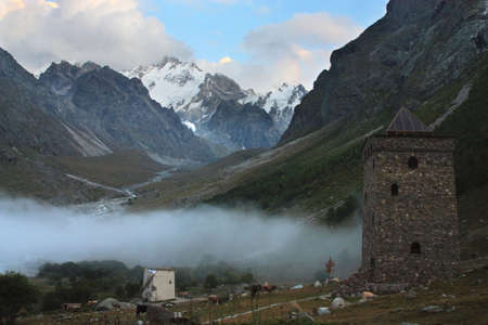 The towers of the ancient mountain village against the backdrop of snow-capped peaks in eveningの写真素材