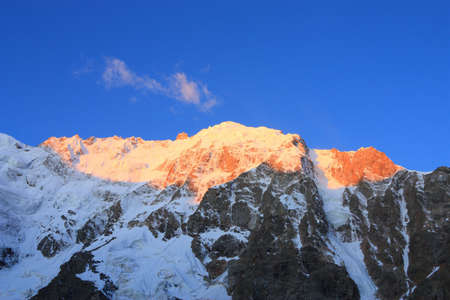 The rays of the rising sun painted the top of the mountain Dykh-tau in golden colorの写真素材