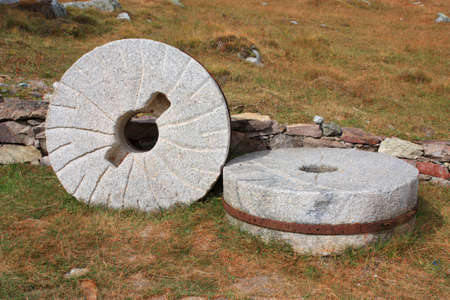 old millstone near the old stone wallの写真素材