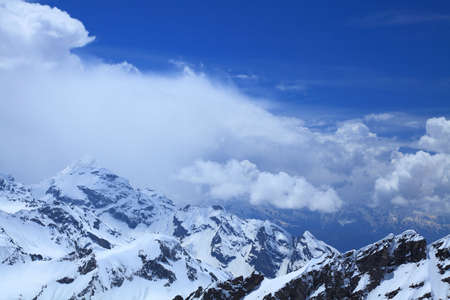 main Caucasus ridge on a background of the blue sky and white clouds