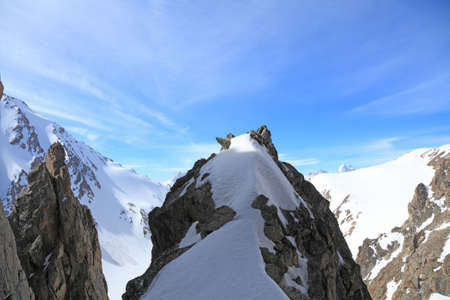 granite rock on a background of snow-capped peaks and blue skyの写真素材
