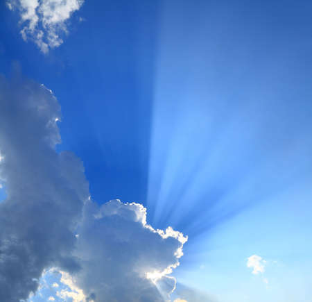 rays of sun beaming through clouds in the blue skyの写真素材